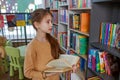 Child girl choosing book in school library. School education. Benefits of everyday reading