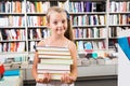 Child girl chose a lot of books in the library Royalty Free Stock Photo