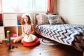 Child girl cleaning her room and organize wooden toys into knitted storage bag