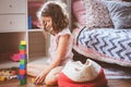 Child girl cleaning her room and organize wooden toys into knitted storage bag