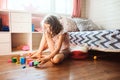 Child girl cleaning her room and organize wooden toys into knitted storage bag