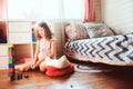 Child girl cleaning her room and organize wooden toys into knitted storage bag