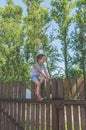 Girl climbs the fence on a summer day Royalty Free Stock Photo