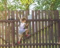 Girl climbs the fence on a summer day Royalty Free Stock Photo