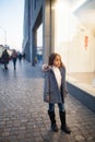 Child girl is standing next to shopwindow on city street in even Royalty Free Stock Photo