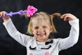 Child girl conjures a magic wand on a black background