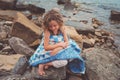Child girl covered in quilt blanket, cozy summer holidays on seaside