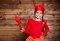 Child girl in devil costume to halloween on a wooden