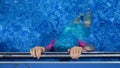 Child girl is diving underwater in swimming pool holding on the metal handrail. Royalty Free Stock Photo