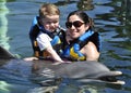 Child and girl with dolphin in blue water. Royalty Free Stock Photo