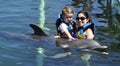 Child and girl with dolphin in blue water. Royalty Free Stock Photo