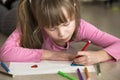 Child girl drawing with colorful pencils crayons heart on white paper. Art education, creativity concept