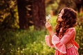 Child girl dressed as fairytale princess playing with blow ball in summer forest