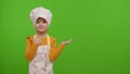 Child girl dressed like chef cook pointing at right on blank space place for your advertisement logo Royalty Free Stock Photo