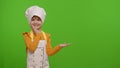 Child girl dressed like chef cook pointing at right on blank space place for your advertisement logo Royalty Free Stock Photo