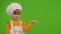 Child girl dressed like chef cook pointing at right on blank space place for your advertisement logo Royalty Free Stock Photo