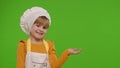 Child girl dressed like chef cook pointing at right on blank space place for your advertisement logo Royalty Free Stock Photo
