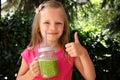 Child girl drinking healthy green vegetable smoothie - healthy eating, vegan, vegetarian, organic food and drink concept Royalty Free Stock Photo