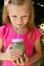 Child girl drinking healthy green vegetable smoothie - healthy eating, vegan, vegetarian, organic food and drink concept Royalty Free Stock Photo