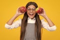 Child girl eating an apple over isolated yellow background. Tennager with fruit. Happy girl face, positive and smiling