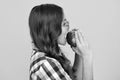 Child girl eating an apple over isolated yellow studio background. Close up face of tennager with fruit. Portrait of Royalty Free Stock Photo