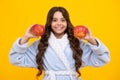 Child girl eating an apple over isolated yellow studio background. Tennager with fruit. Portrait of happy funny smiling