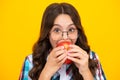 Child girl eating an apple over  yellow studio background. Close up face of tennager with fruit. Portrait of Royalty Free Stock Photo