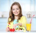 Child girl eating fresh salad vegetables at table indoors. Royalty Free Stock Photo