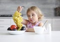 Child girl eating fruits. Little girl have a healthy meal at kitchen. Nutrition concept. Organic food. Curiosity