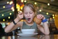 Child girl eating soup and tasty burger in restaurant Royalty Free Stock Photo