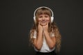 child girl enjoys music in her big white headphones and smile.Blue eyes blonde hair girl listen to music