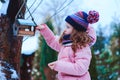 child girl feeding birds in winter. Bird feeder in snowy garden, helping birds during cold season Royalty Free Stock Photo