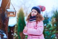 Child girl feeding birds in winter. Bird feeder in snowy garden, helping birds during cold season Royalty Free Stock Photo