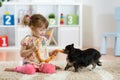 Child girl feeding sausages to her dog on floor in nursery. Royalty Free Stock Photo