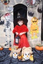 A child girl in the form of a witch on a broomstick, poses against the backdrop of pumpkins on Halloween holiday . Girl