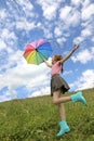 Child a girl with a great mood jumps in the summer in a field with a rainbow umbrella