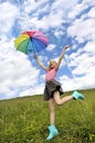 Child a girl with a great mood jumps in the summer in a field with a rainbow umbrella