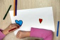 Child girl hands drawing with colorful pencils crayons heart on white paper. Art education, creativity concept
