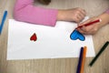 Child girl hands drawing with colorful pencils crayons heart on white paper. Art education, creativity concept