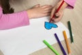 Child girl hands drawing with colorful pencils crayons heart on white paper. Art education, creativity concept