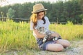 Child girl in hat with gray fluffy cat in her arms. Beautiful sunset country landscape background Royalty Free Stock Photo