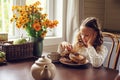 Child girl having breakfast at home in autumn morning. Real life cozy modern interior in country house Royalty Free Stock Photo