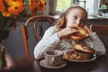 Child girl having breakfast at home in autumn morning. Real life cozy modern interior in country house Royalty Free Stock Photo