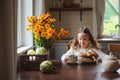 Child girl having breakfast at home in autumn morning. Real life cozy modern interior in country house