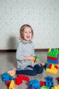 Child girl having fun and build of bright plastic construction blocks. Toddler playing on the floor. Developing toys. Early Royalty Free Stock Photo