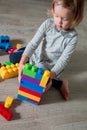 Child girl having fun and build of bright plastic construction blocks. Toddler playing on the floor. Developing toys. Early learni Royalty Free Stock Photo