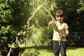 Child girl having fun with watering trees and plants in domestic garden Royalty Free Stock Photo