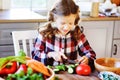 Child girl helps mom to cook and cut fresh vegetables for salad with knife Royalty Free Stock Photo