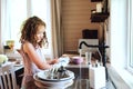 Child girl helps mother at home and wash dishes in kitchen. Casual lifestyle in real interior