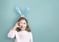 Caucasian child girl holding Easter egg on blue empty space background. Happy cute smiling bunny kid easter backdrop Royalty Free Stock Photo